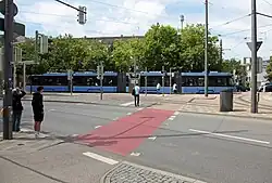 München, Duitsland — Een schoolvoorbeeld van drempelvrije toegankelijkheid: brede, vlakke trottoirs, duidelijke geleidelijnen en een naadloze overgang tussen straat en gebouw. Deze stedelijke omgeving toont hoe toegankelijkheid kan worden geïntegreerd in het dagelijks leven.