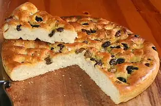 Een focaccia met olijven, rozemarijn en salie.