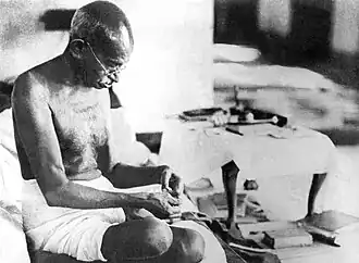 Mahatma Gandhi gebruikt een spinnewiel.