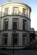 Pand, dat het rechter gedeelte van de afrondende rechterhoek vormt van een in het derde kwart van de 19e eeuw als een symmetrisch geheel ontworpen straatwand