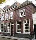 Twee huizen, onder afzonderlijke schilddaken, het linkse met een lijstgevel in schoon werk en met een geblokte ingangsomlijsting, het rechtse gebosseerd roze gepleisterd