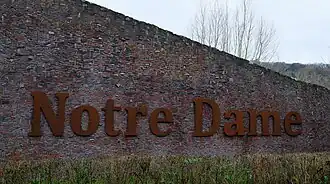 Geluidswerende muur van afgekeurde bakstenen (noordzijde van het huidige schoolgebouw)