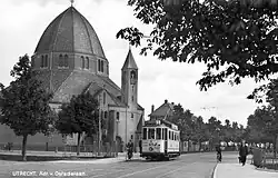 Motorwagen 65 op lijn 3 van de Gemeentetram Utrecht (GTU) passeert de Sint-Aloysiuskerk aan de Adriaen van Ostadelaan 2 te Utrecht; circa 1933-1938. Collectie van het Utrechts Archief.