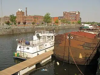 kleurenfoto van kanaal met boot en textielfabriek
