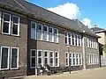Schoolgebouw, gebouwd als onderdeel van het complex 'Gerardus Majellakerk'. Het schoolgebouw, in oorsprong een meisjesschool in rationalistische trant, ligt ter hoogte van het koor, binnen de rooilijnen van het rechthoekige terrein van de R.K enclave rond de kerk