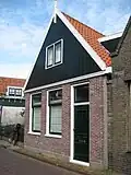 Eenvoudig huisje met vernieuwde top en in de zijgevel een sieranker. Houtskeletbouw