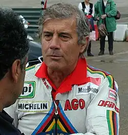 Giacomo Agostini laat zich nog graag zien bij demonstratieraces of bijeenkomsten met klassieke motorfietsen. Deze foto is gemaakt tijdens de Coupes Moto Légende in Monthlery (Frankrijk) in 2003. Hij was toen 61 jaar oud.