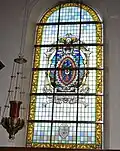 Glasraam werd betaald door de familie de Viron. Hun wapenschild werd in het raam verwerkt.