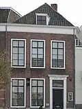 Pand met lijstgevel. Dakkapel. Voordeuromlijsting met gecanneleerde pilasters. Zandstenen plint