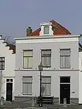 Huis met gepleisterde lijstgevel. Dakkapel met wangstukken