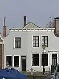Met de bocht van de kade meegebouwd dubbel pand met gepleisterde ingezwenkte lijstgevel. Nr 37: voordeuromlijsting
