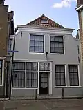 Huis met gepleisterde ingezwenkte lijstgevel. Winkelpui