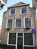 Huis met afgeknotte topgevel. Staafankers. Winkelpui