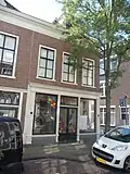 Hoekpand Zusterstraat onder schilddak, waarin dakvenster met vleugelstukken. Lijstgevel met in de verdieping Empire-schuiframen
