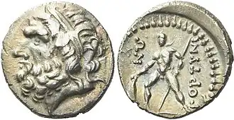 Drachme van Gortys, geslagen circa 98-94 v.Chr., zilver, diameter 17 mm, gewicht 3,14 g. De voorzijde toont het diadeemdragende hoofd van Zeus naar links, symbool van kracht en goddelijkheid in de Griekse wereld. Op de keerzijde staat een krijger afgebeeld, staand naar links, met een schild en speer, een verwijzing naar de militaire cultuur van de stadstaat Gortys. De inscriptie "ΓΟΡΤΙΝΙΩΝ" verwijst naar de stad zelf.