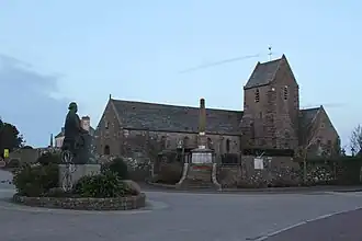 De kerk van Gréville-Hague met het standbeeld van Jean-François Millet op het plein ervoor