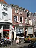 Huis met schilddak en eenvoudige lijstgevel; schuiframen; winkel