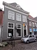Huis met hoog schilddak en lijstgevel, kroonlijst met klossen, triglyphen en druppen, deuromlijsting en gesneden bovenlicht