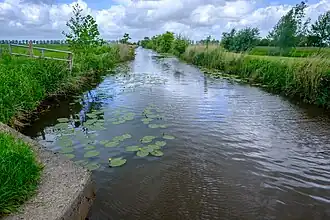 De Grootegastertocht in de Westzandemermolenpolder gezien vanaf de Abel Tasmanweg/Westerzand naar het noorden. Het water vormt de scheiding tussen de dorpsgebieden van Lutjegast en Sebaldeburen.