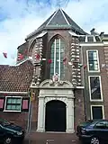 Ingangspoort van koor van Sint Janskerk met natuursteen versierd, door Haarlems wapen in cartouche bekroond