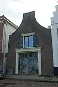 Pand met klokgevel, stalgebouw, getande lijst boven de ingang