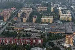 Metrostation met groen beschilderde loopbrug en de zuidelijke ingang, met groene biezen, tussen de hoogbouw aan de Skarbrunnavägen
