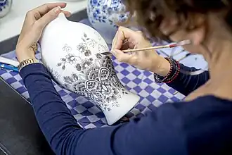 Wanneer de plateelschilder de verf aanbrengt is deze nog grijs. Na het verhitten komt de karakteristieke Delfts blauwe kleur tevoorschijn