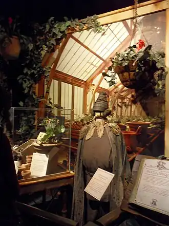 Kledij van Pomona Stronk met op de achtergrond de plantenkassen van Zweinstein