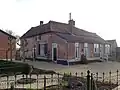 Boerderij, met omlopend rieten dak en links een opkamer. Deur getoogd en gesneden kalf
