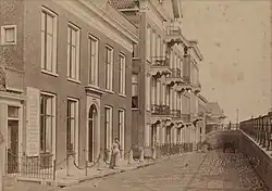Woningen aan westzijde van de Hereweg naast het oorspronkelijke Herewegviaduct rond 1890. In de jaren 1930 werd de straat door de uitbreiding van het viaduct met een overkraging sterk versmald. Een aantal woningen werd daarvoor gesloopt. Van de oorspronkelijke bebouwing resteert alleen het zuidelijke en middendeel van het pand met de balkons.