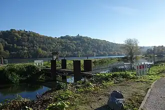Een bruggetje over de oude Maasarm, met op de achtergrond de Maas.