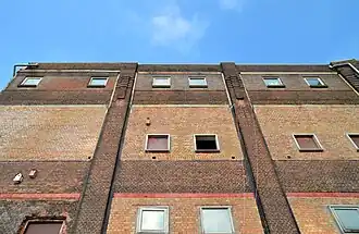 Voorgevel tarwestijfselgebouw met druipsteenmotieven op bovenste verdieping en frontonvormige attieken