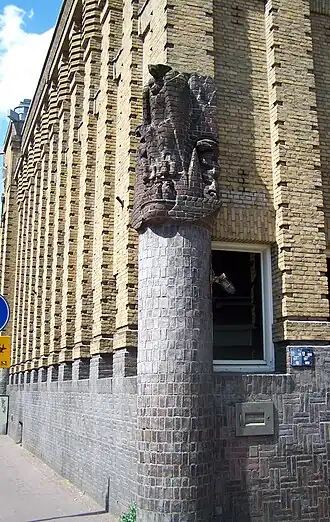 Baksteensculptuur van Hildo Krop met een adelaar en diens jongen in een nest omgeven door slangen