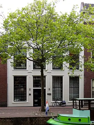 Pand Hoge Gouwe 77 met gepleisterde lijstgevel onder zeer rijk gesneden lijst, Lod.XIV. Breedte: vier vensterassen, geprofileerde hardstenen vensterdorpels en schuiframen