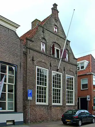 Huis met gerestaureerde puntgevel met zandstenen waterlijsten en afdekplaten en uitgekraagde toppilaster op zandstenen console met engelenkopje[4]