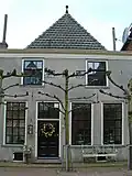 Huis met eenvoudige gepleisterde gevel met rechte kroonlijst, twee gevelstenen met eenhoorns in rolwerk-cartouches, steen met engelenkopje en sierankers (Huis met de eenhoorn)