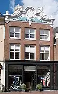 Huis met drie traveeën brede gevel afgesloten door rijk gesneden verhoogde kroonlijst met figuren van Handel en Zeevaart en vazen