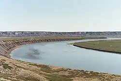 A big river winds across a plain near a bluff.
