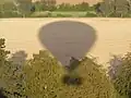 Schaduw van een heteluchtballon op bomen en de grond