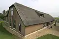 Boerderij onder rieten wolfdak. Uitgebouwde opkamer. In de voorgevel vlechtingen en stermotieven in het metselwerk. Sieranker. Vensters met luiken en zesruitsschuiframen. Recht op het erf een houten schuur met pannen zadeldak