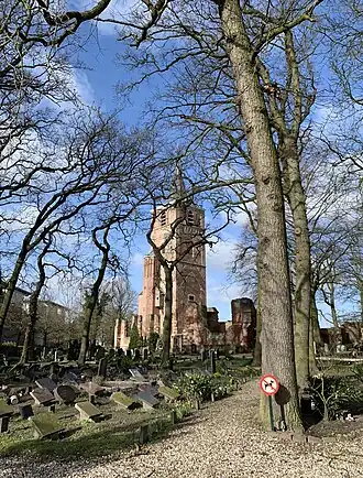 Zicht op de oude toren en de ruïne vanuit de ingang van het kerkhof.