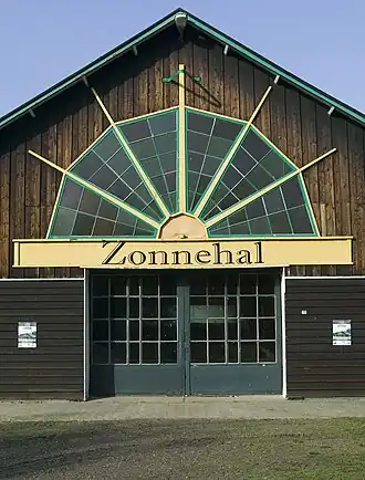 Ingangspartij, toegangsdeur met groot bovenlicht, als ware een opkomende zon met zonnestralen