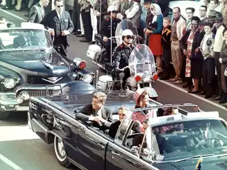 John F. Kennedy (links) en zijn vrouw in de limousine, kort voor de aanslag