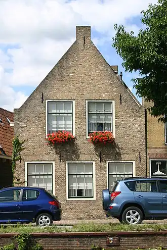 Pand met gepleisterde puntgevel vensters met roedenverdeling in stijl