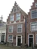 Huis met trapgevel met in het fries leeuwenmasker, een steen met voorstelling van een struisvogel en twee steentjes met anno en 1662 in vredeman de vries ornament