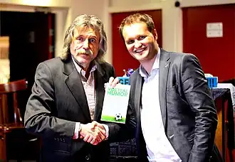 Overhandiging van het eerste exemplaar van het boek Voetbalhumor van Groenendijk aan Johan Derksen.
