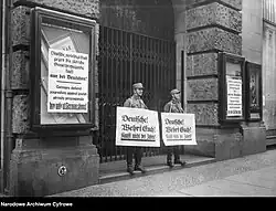 Leden van de Sturmabteilung voor de ingang van een winkelpand met een bord met daarop de tekst "Duitsers! Verzet u! Koop niet bij Joden!"