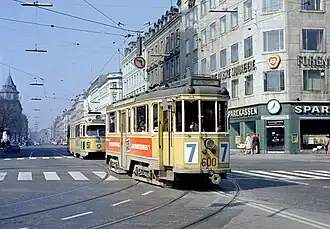 Vierassige motorwagen 600 op lijn 7, gevolgd door een gelede wagen op lijn 5 op de Frederiksborggade / Nørre Voldgade / Nørreport Station; 6 april 1969.