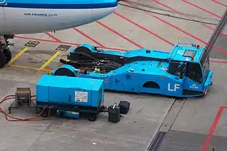 KLM pushback truck met ervóór een Ground Power Unit (GPU)