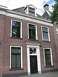 Pand met lijstgevel op plint met door pilasters en kroonlijst omlijste voordeur en dakkapel met omlijsting